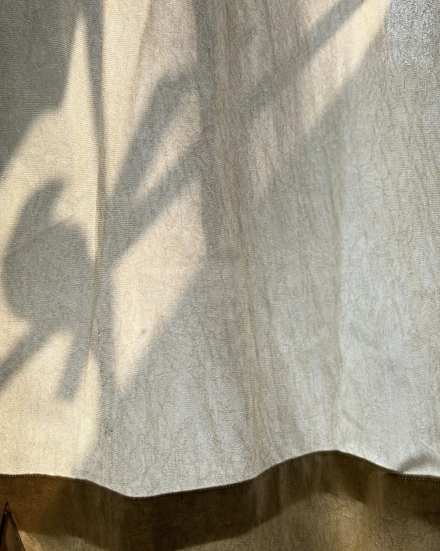 The shadow of a plant on a linen curtain